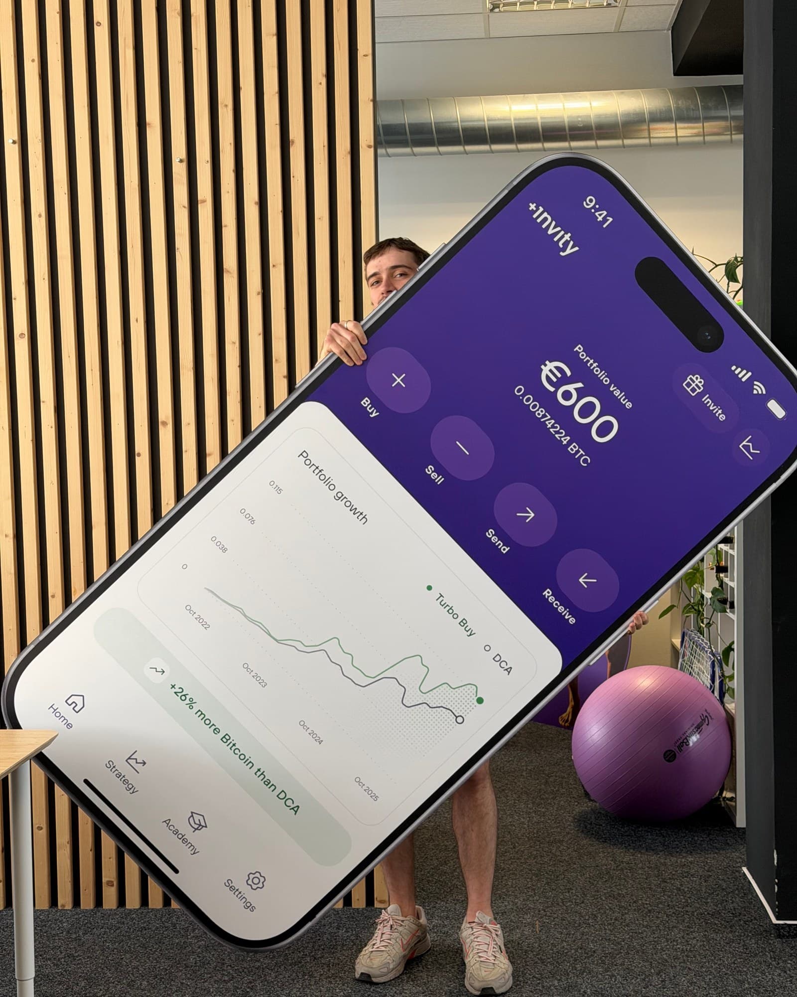Anton peeking from behind a life-size print of the Invity app